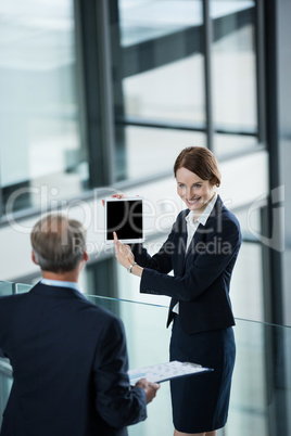 Businesswoman showing digital tablet to her colleague