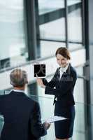 Businesswoman showing digital tablet to her colleague