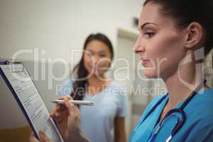 Female nurse writing on clipboard