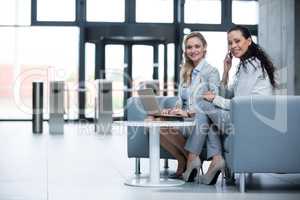 Businesswomen using laptop and talking on mobile phone
