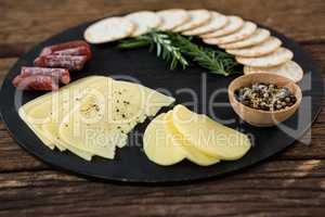 Slices of cheese, nacho chips and rosemary herbs on plate