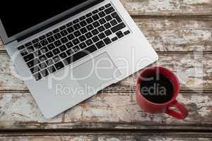 Cup of coffee and laptop on wooden table