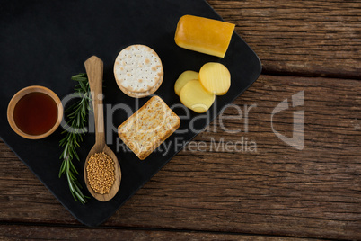 Cheese, crackers, nacho chips and rosemary herbs on slate plate