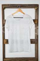 White t-shirt hanging on wooden frame