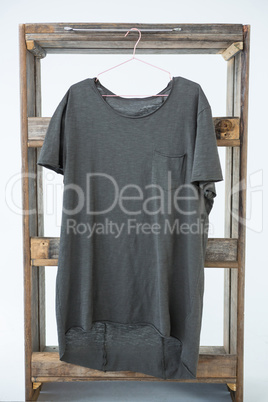 Grey t-shirt with pocket hanging on wooden frame
