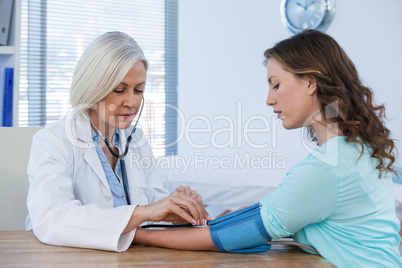 Female doctor checking blood pressure of a patient