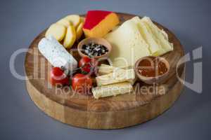 Variety of cheese, cherry tomato and sauce on wooden board