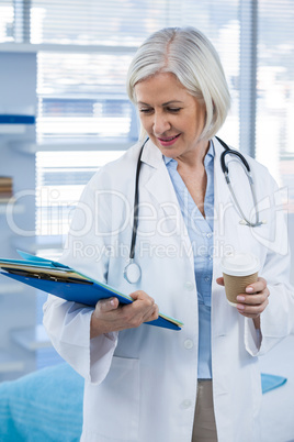 Female doctor holding medical file and coffee cup