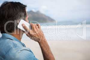 Man talking on mobile phone on beach