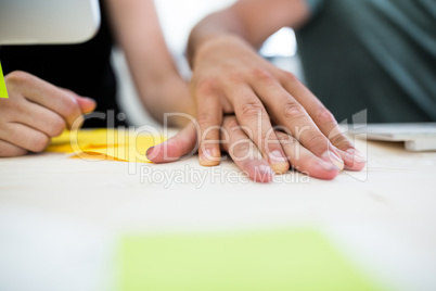 Close-up of office colleagues with hand on hand at desk