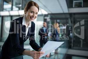Businesswoman standing in corridor reading document in office
