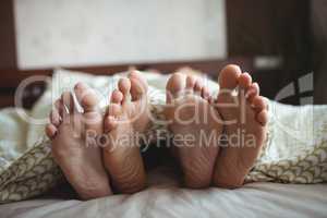 Couple showing their feet while lying on a bed