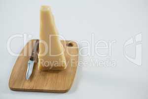 Piece of cheese with knife on cutting board