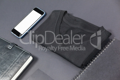 Folded t-shirt, smartphone, diary, card and note pad