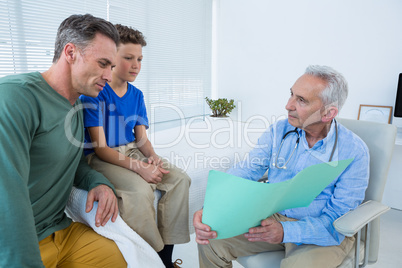 Doctor showing medical report to patient and his parent