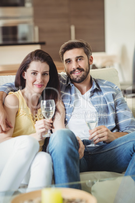 Happy couple relaxing on sofa and holding glasses of champagne