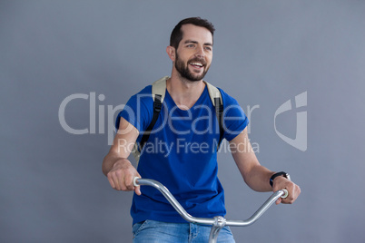 Man in blue t-shirt and back posing sitting on a bicycle