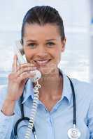 Smiling female doctor talking on telephone