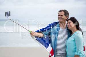 Couple wrapped in american flag taking selfie on beach