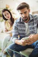 Couple using mobile phone on sofa