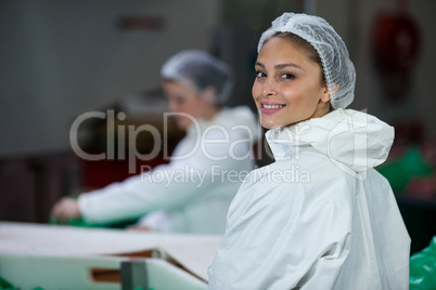 Smiling butcher standing in meat factory