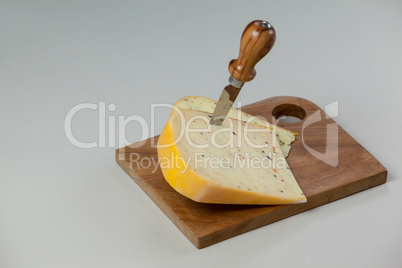 Knife on cheese slices on wooden board