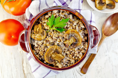 Buckwheat with mushrooms in clay bowl on towel top