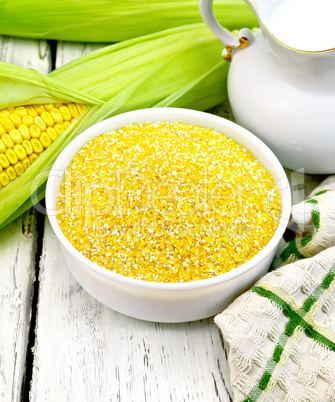 Corn grits in bowl with milk on board