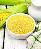 Corn grits in bowl with milk on board