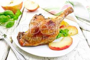 Duck leg with apple in plate and napkin on board
