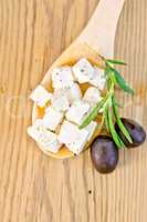 Feta with olives in spoon on board
