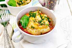 Fish baked with tomato and basil in white bowl on board