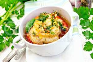 Fish baked with tomato and spices in white bowl on board