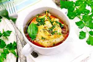 Fish baked with tomato in white bowl on board
