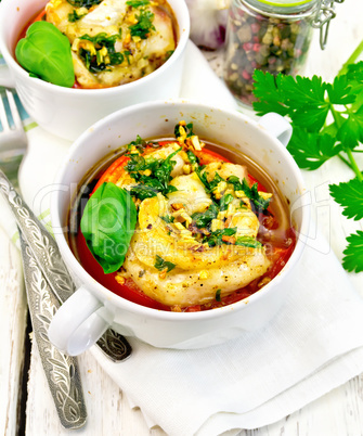 Fish baked with tomato in white bowl on linen napkin