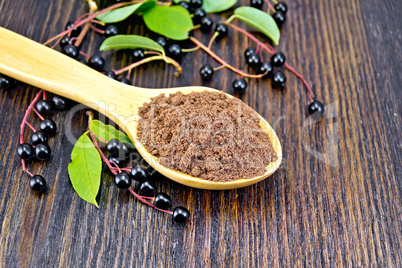 Flour bird cherry in spoon with berries on wooden board