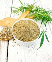 Flour hemp in bowl with spoon and leaf on board