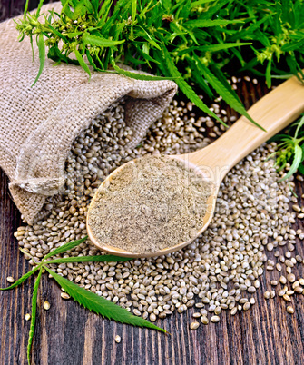 Flour hemp in spoon with leaf and bag on board