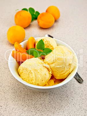 Ice cream apricot in white bowl on table with spoon