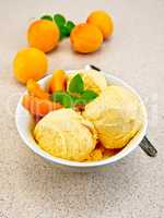 Ice cream apricot in white bowl on table with spoon