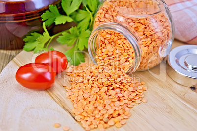 Lentils red in glass jar with tomatoes on board