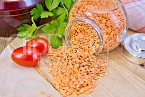 Lentils red in glass jar with tomatoes on board