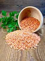 Lentils red in wooden bowl with parsley on board