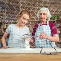 Grandmother and granddaughter sifting flour