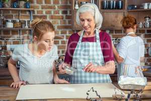 Grandmother and granddaughter sifting flour