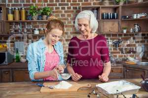 Grandmother and granddaughter sifting flour