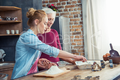 Grandmother and granddaughter sifting flour