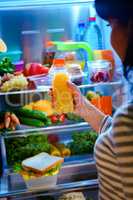 Woman takes the Orange juice from the open refrigerator