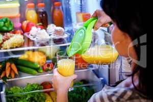 Woman takes the Orange juice from the open refrigerator
