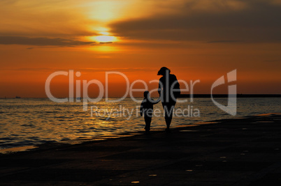 Woman with child holding hands run along the sea promenade